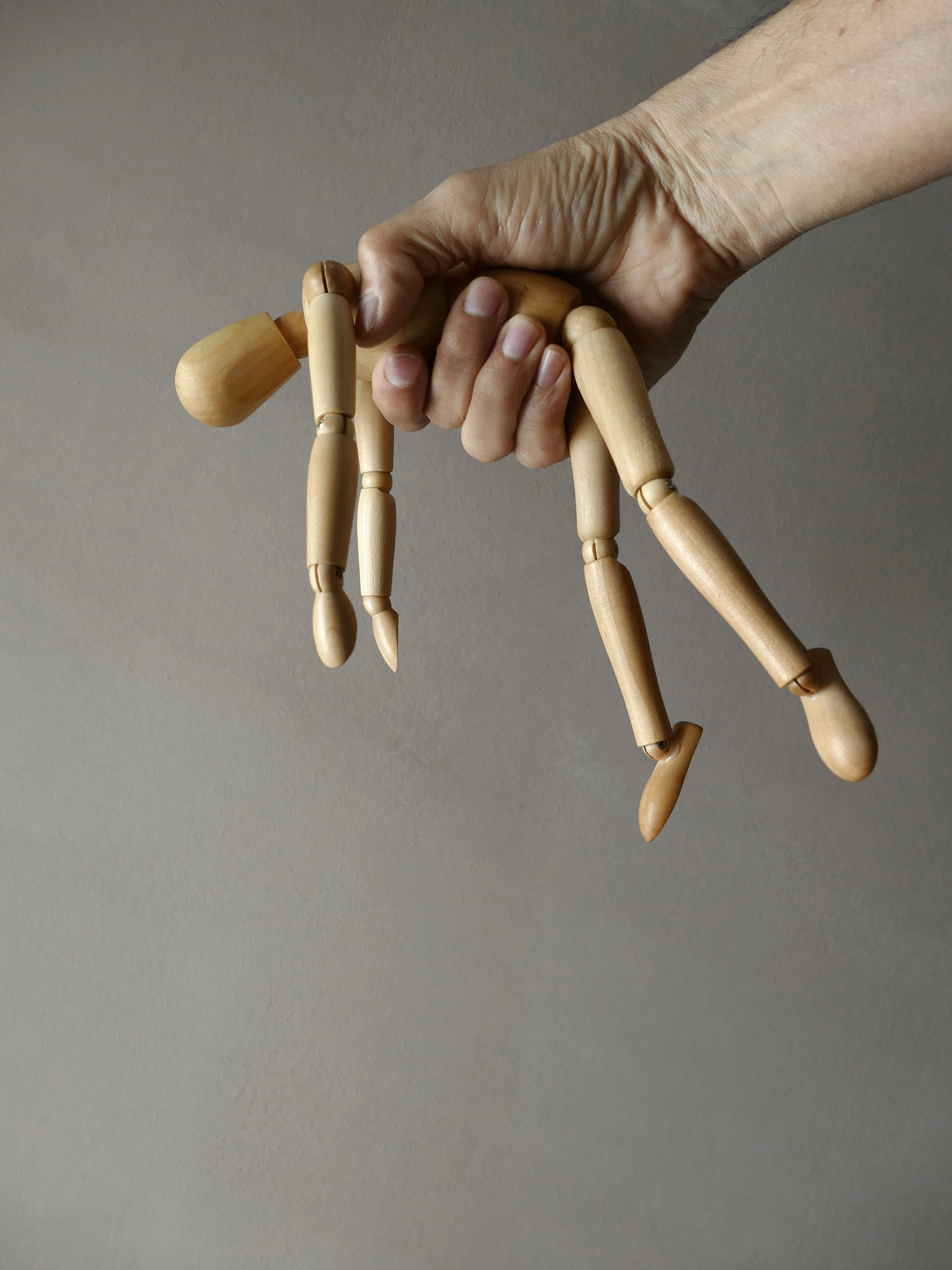 person holding brown wooden mannequin